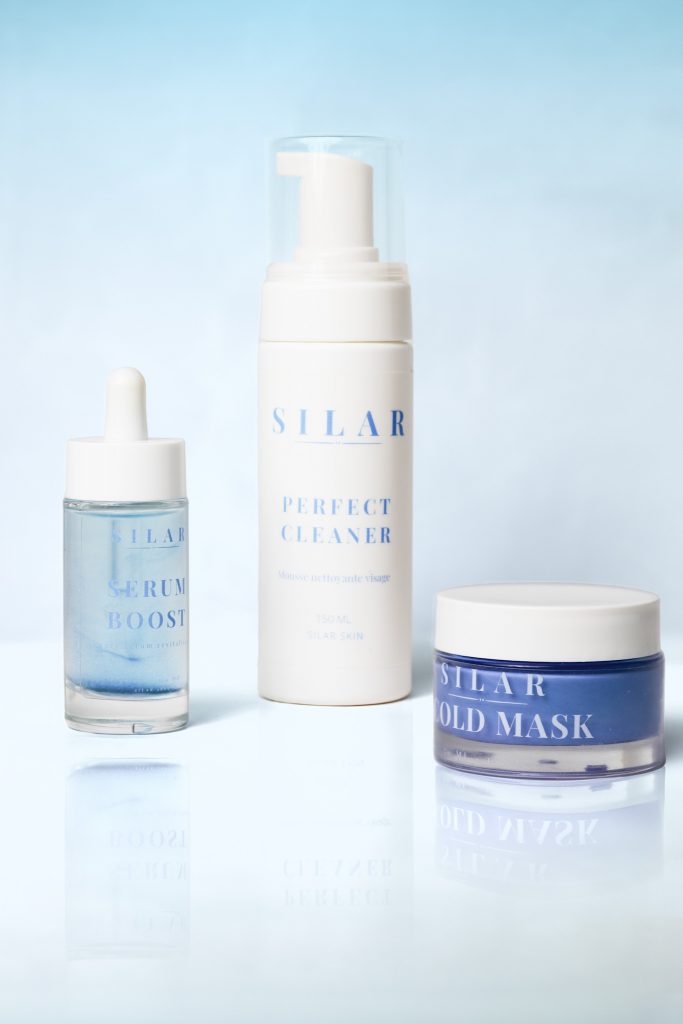 Photographie Packshot de trois produits cosmétiques sur fond bleu.